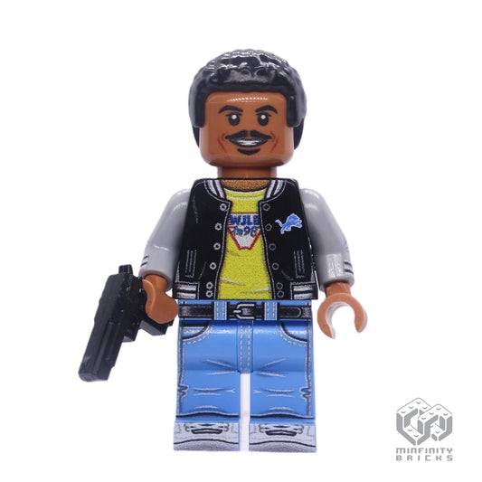 A custom LEGO minifigure of the character Detective Foley from the movie Beverly Hills Cop, featuring a black torso, gray and blue jeans, a white jacket with a badge, and a black pistol.